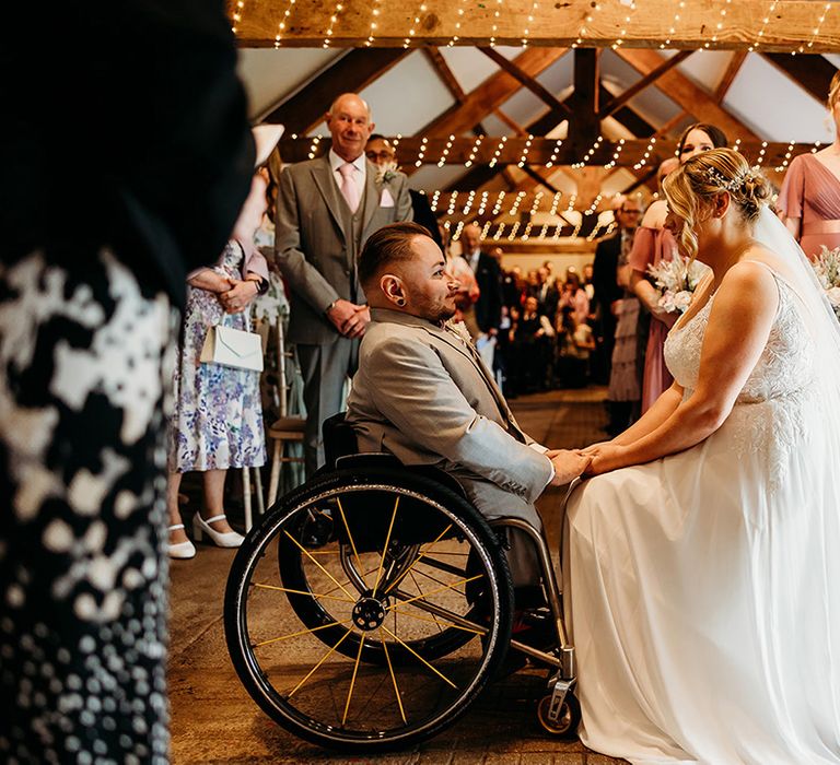 bride-sits-on-stool-for-wooden-ceremony-for-interabled-wedding-ceremony.