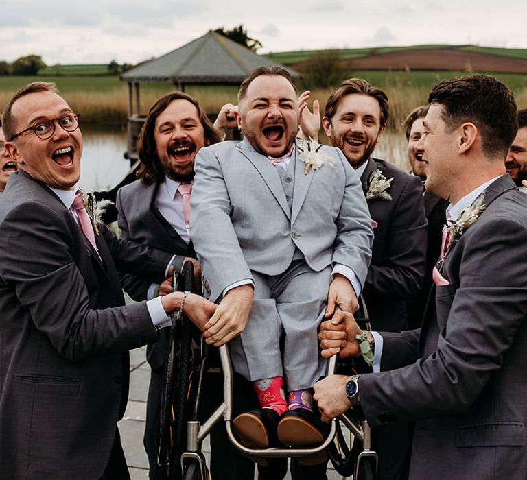 groomsmen-lift-groom-up-in-wheelchair-at-quantock-lakes-wedding-venue