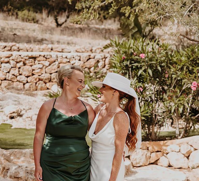 maid-of-honour-in-emerald-green-satin-bridesmaid-dress-with-bride-wearing-white-bridal-hat-stephanie-shenton-photograph