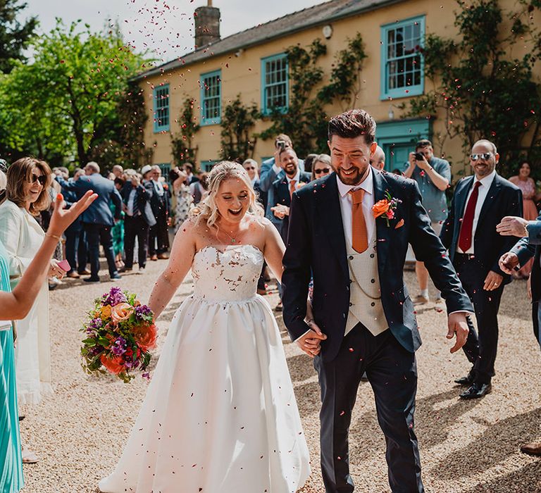 bride-and-groom-walking-out-of-wedding-venue-to-confetti