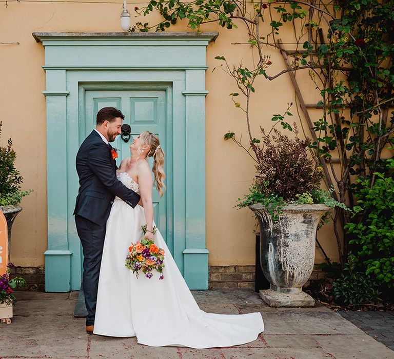 couple-portrait-of-bride-and-groom-with-colourful-wedding-welcome-sign