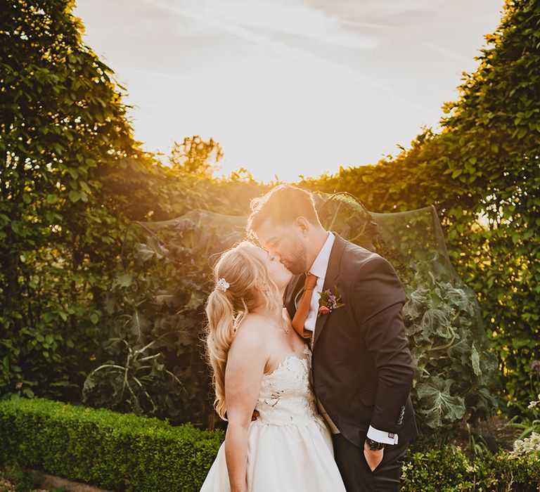 golden-hour-couple-portrait-with-bride-in-strapless-wedding-dress-kissing-groom