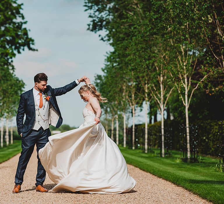 groom-in-three-piece-wedding-suit-spins-bride-around-in-couple-portrait