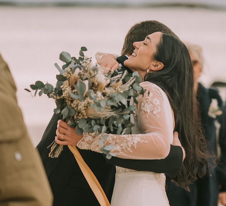 bride-wearing-lace-wedding-dress-with-foliage-bouquet