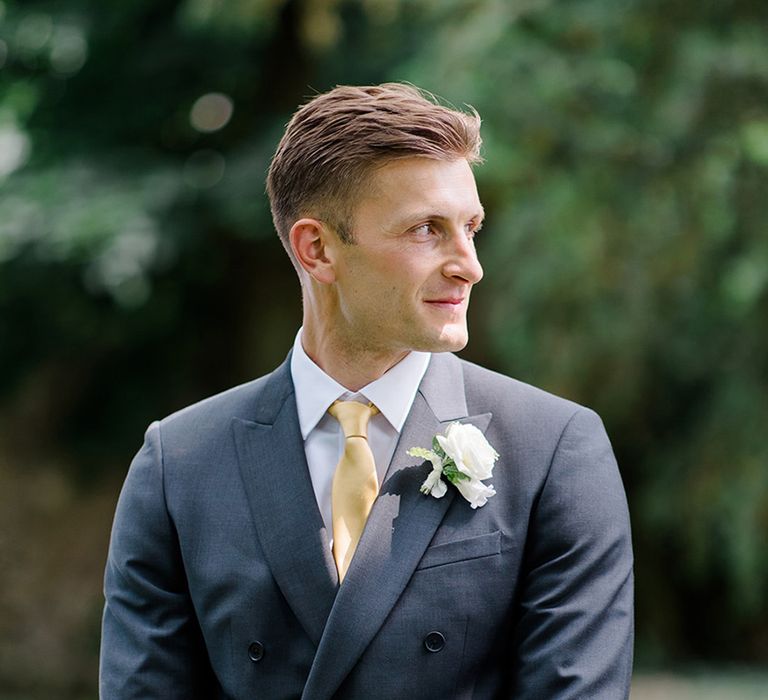 groom-in-navy-suit-with-yellow-tie-and-white-rose-buttonhole