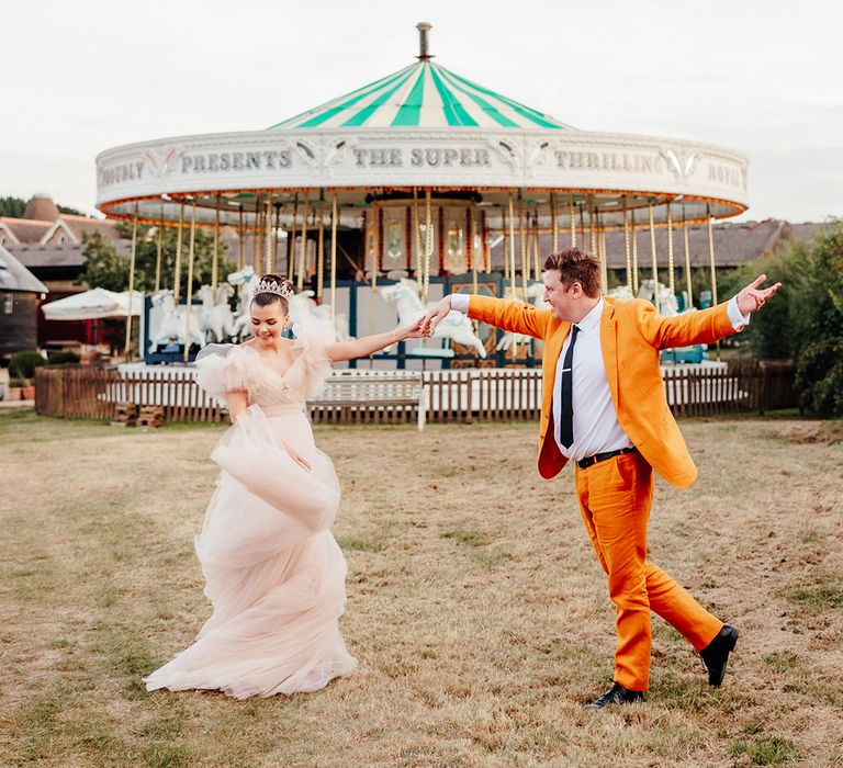 bride-in-pink-wedding-dress-with-groom-in-yellow-suit-at-fairground-wedding