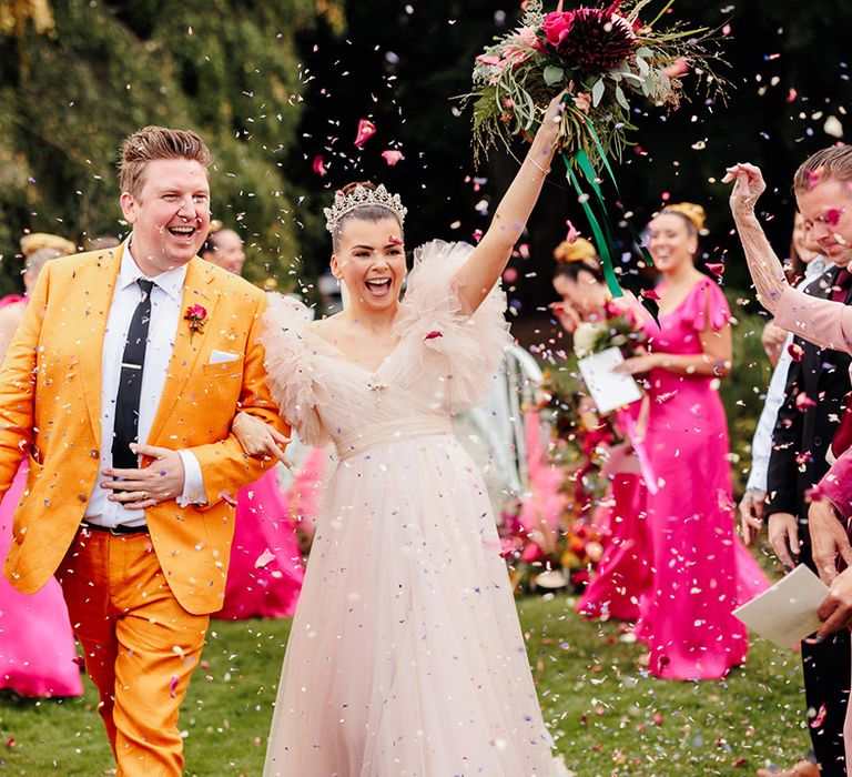 confetti-moment-for-bride-in-princess-dress-and-crown-with-groom-in-yellow-suit