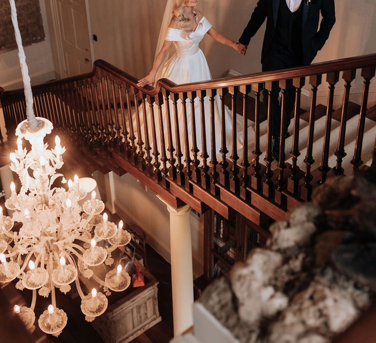 groom-leads-the-bride-upstairs-at-country-house-wedding