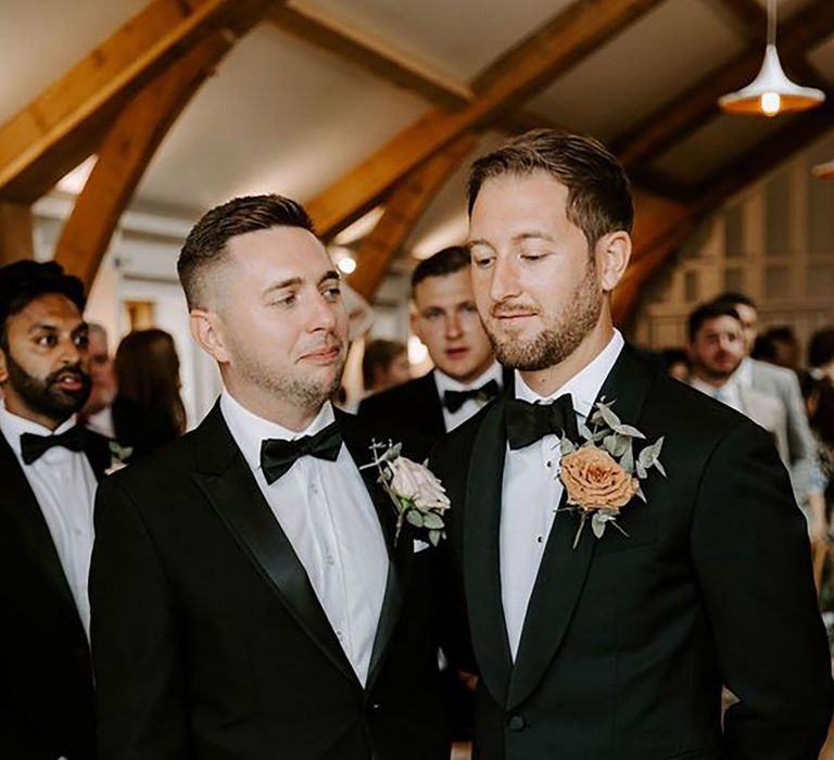 groom and best man wearing matching black tie wedding suits