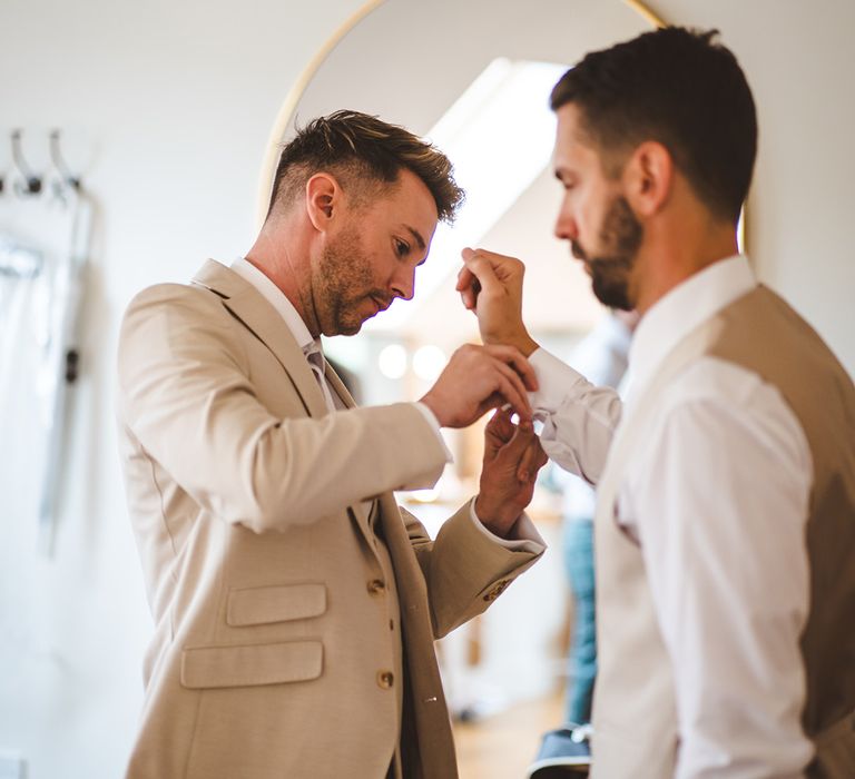 groomsman-gets-ready-for-wedding-day-wearing-cream-and-beige-wedding-suit