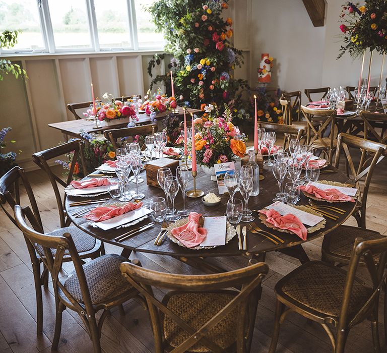 round-tables-decorated-with-pink-napkins-candles-and-vibrant-flowers