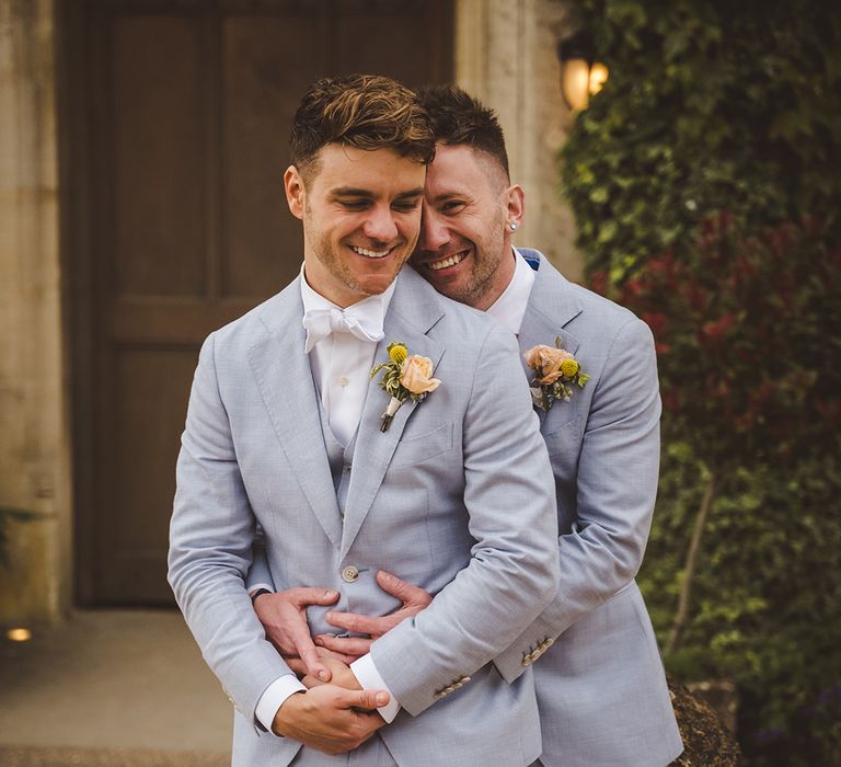 two-grooms-in-light-blue-wedding-suits-with-yellow-buttonholes