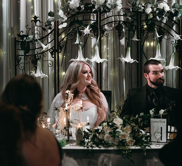 bride-and-groom-sitting-at-sweetheart-table-with-trumpet-flowers