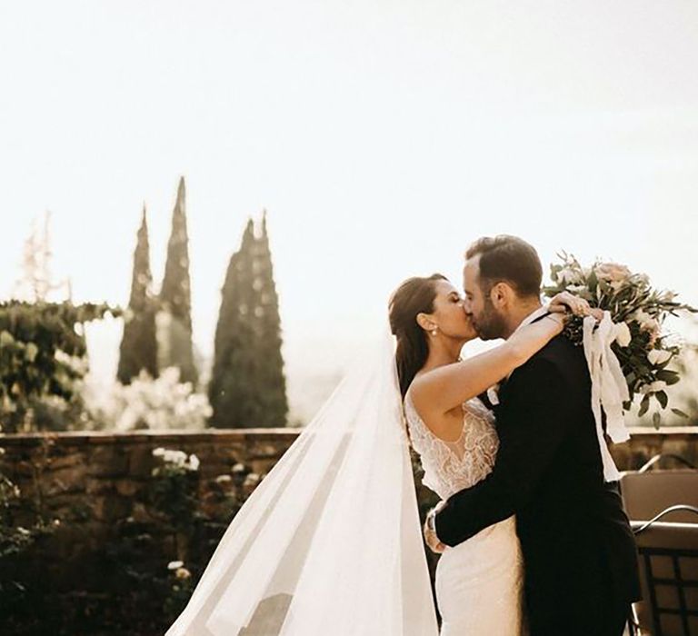 bride wearing a bespoke wedding dress, while kissing groom on wedding day