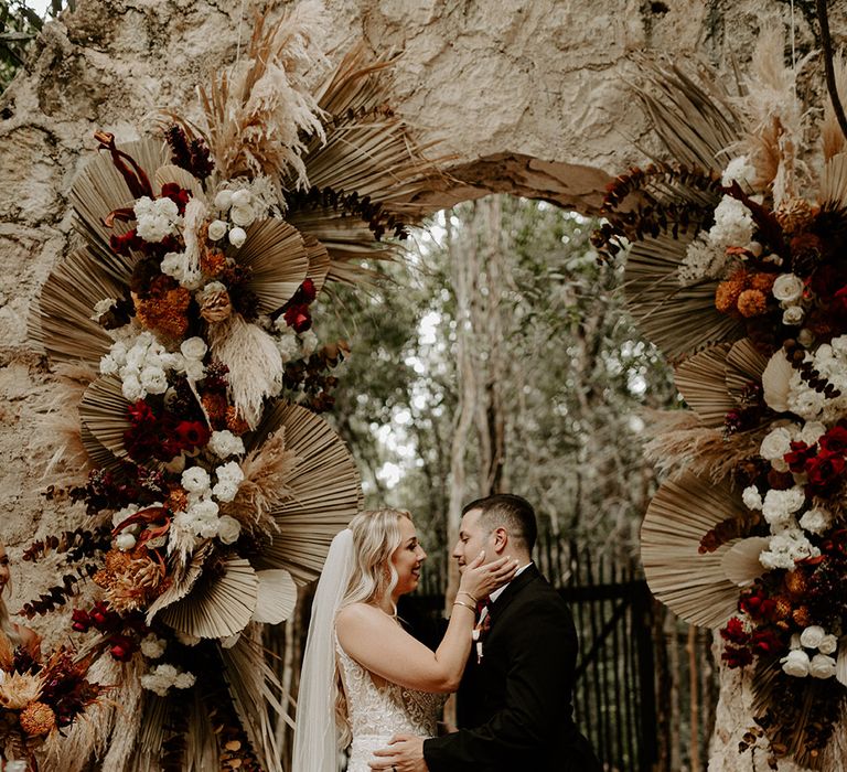 dried-palm-leaves-and-flowers-decorating-altar-space-at-outdoor-wedding