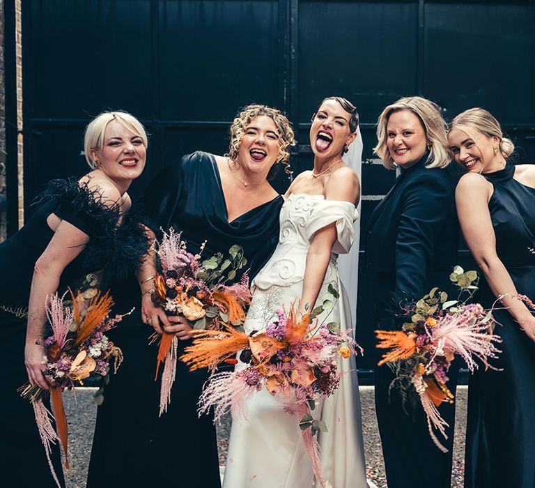 bridal-party-wearing-black-bridesmaid-dresses-holding-pink-and-yellow-dried-wedding-bouquets