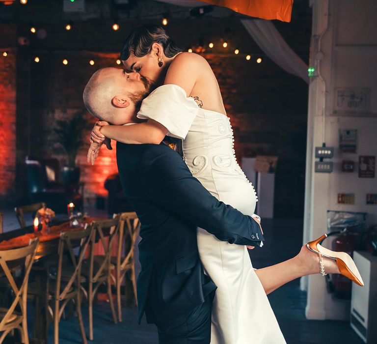 groom-lifts-bride-wearing-vintage-wedding-dress-at-wedding