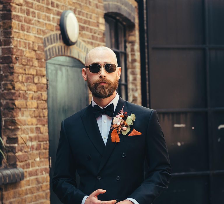 groom-wearing-black-tie-with-double-breasted-wedding-suit-with-orange-buttonhole-and-sunglasses