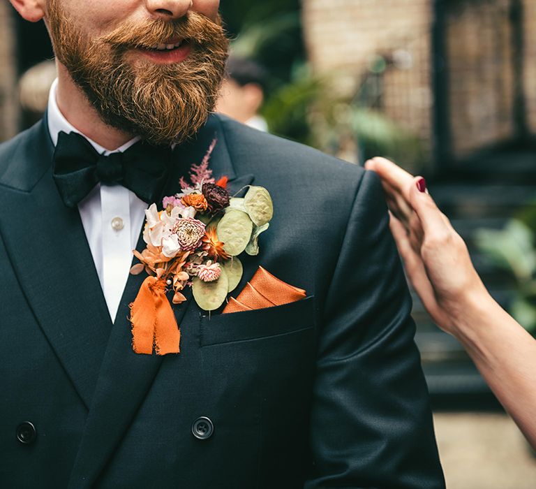 groom-wearing-double-breasted-wedding-suit-with-orange-flower-wedding-buttonhole