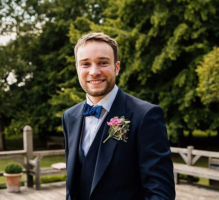 groom wearing traditional three piece blue suit on wedding day