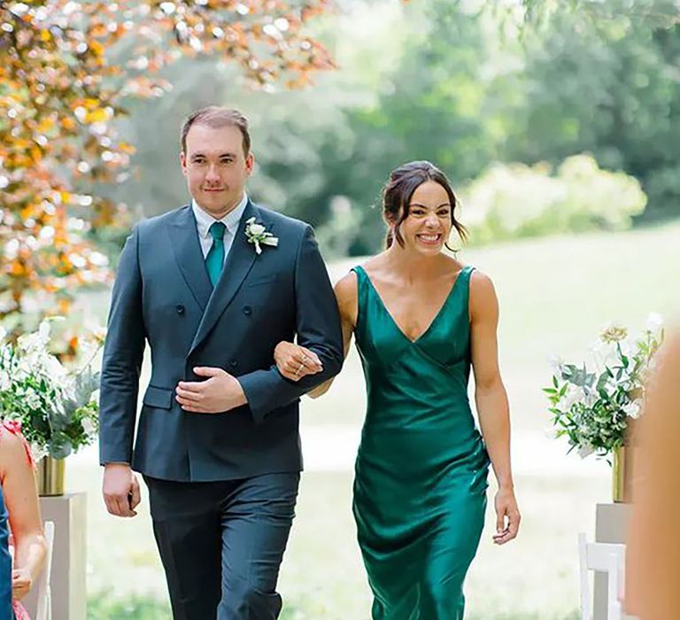 bridesmaid wearing green satin bridesmaid dress, walking down aisle