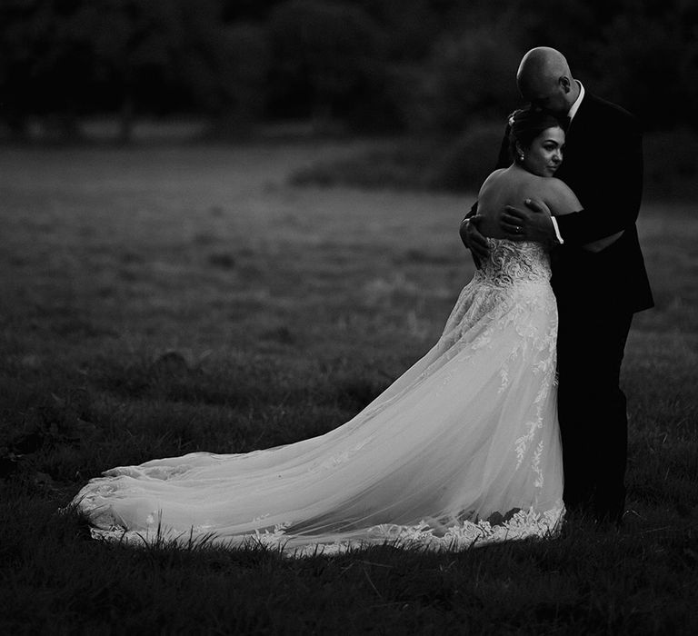 bride-in-strapless-wedding-dress-with-princess-skirt-and-train-embracing-groom