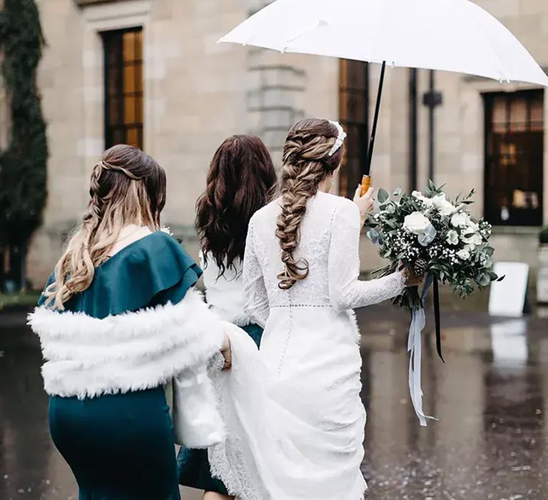 bride wearing winter wedding dress and wedding guest/ bridesmaid wearing teal satin gown with fur shawl 