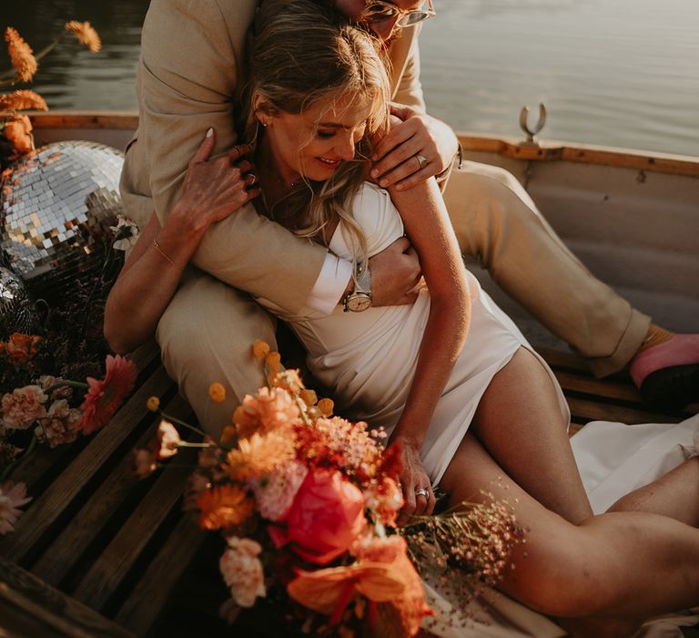 bride-and-groom-in-row-boat-with-pink-and-orange-flowers