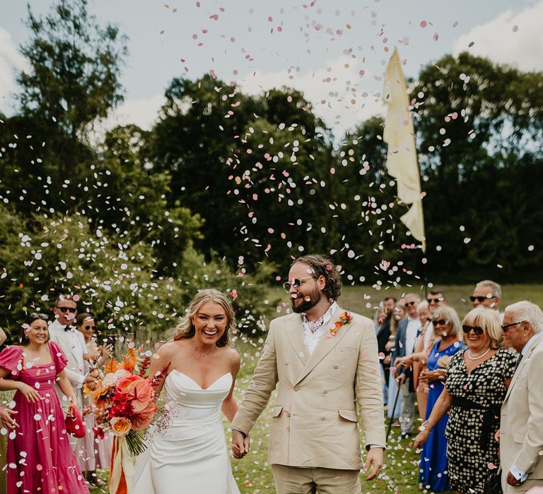 bride-in-strapless-wedding-dress-with-groom-in-beige-suit-confetti-moment