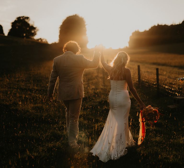 golden-hour-wedding-photo-of-bride-and-groom-holding-hands