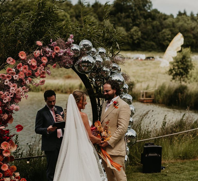 groom-in-beige-wedding-suit-with-bride-wearing-wedding-dress-with-train-at-outdoor-festival-wedding