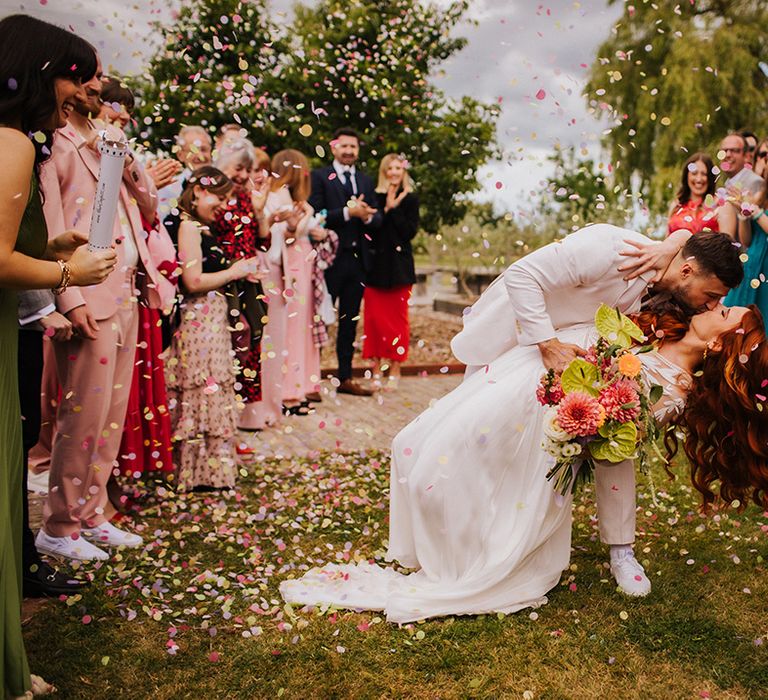 confetti-moment-as-groom-kisses-bride-in-romantic-kiss