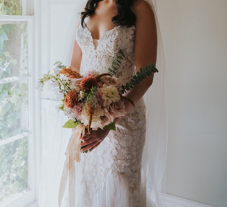 bride-wearing-floral-lace-mermaid-wedding-dress-with-flower-bouquet