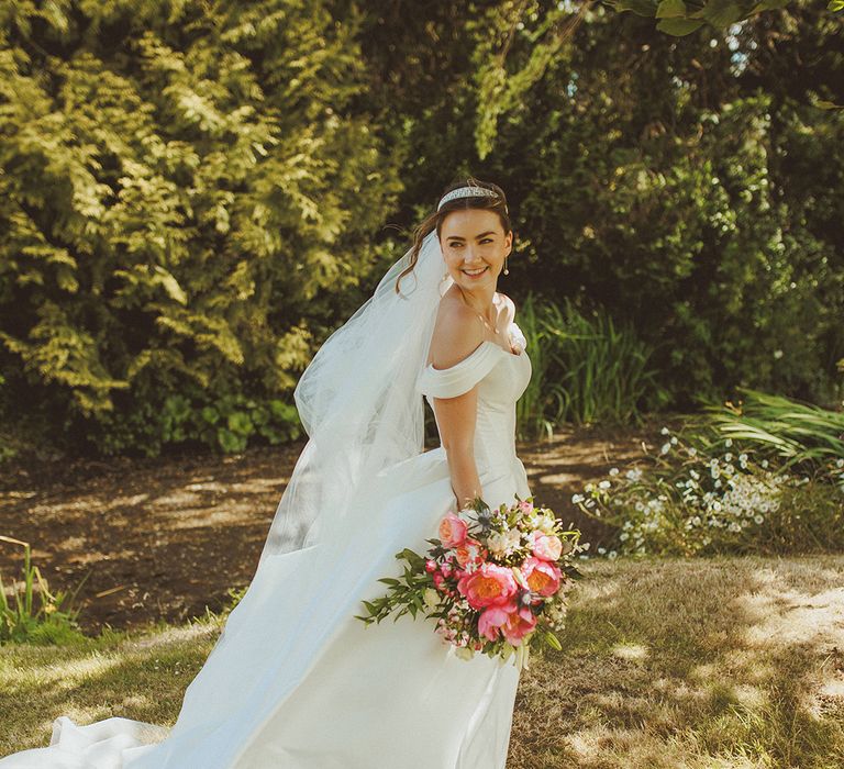 bride-wearing-wedding-veil-with-off-the-shoulder-detail-with-pink-bouquet