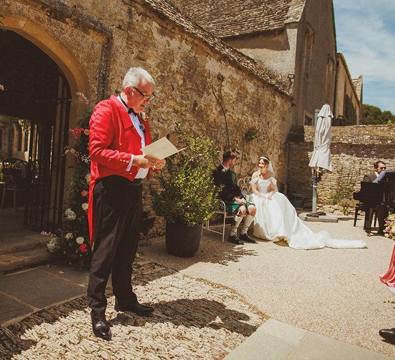 wedding-reading-at-outdoor-wedding-ceremony-by-guest-in-pink-suit-jacket