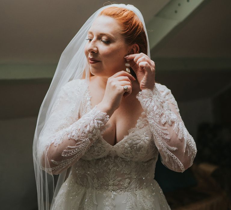 bride-in-lace-wedding-dress-putting-in-earrings