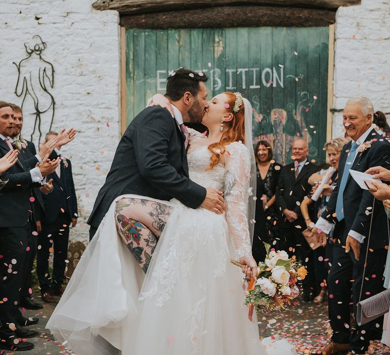 groom-kisses-bride-with-tattooed-leg-peeking-out-of-wedding-dress