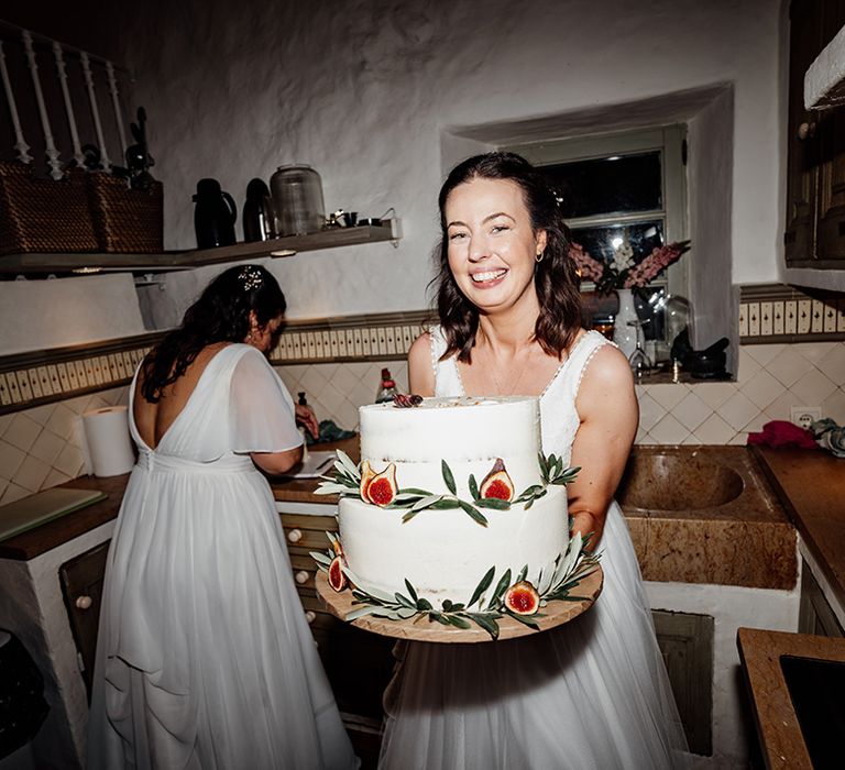 bride-poses-with-rustic-two-tier-wedding-cake