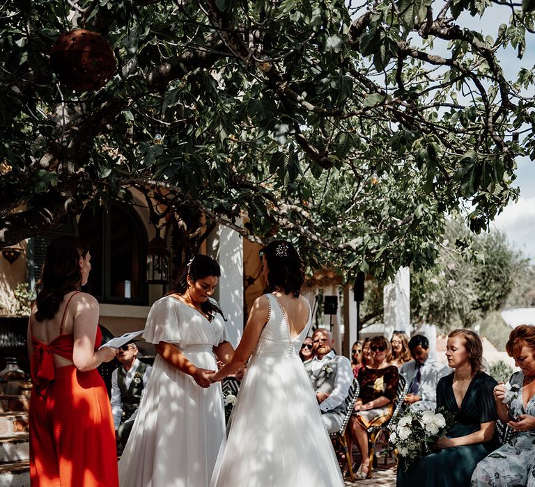 brides-holding-hands-as-they-exchange-vows-at-wedding-ceremony