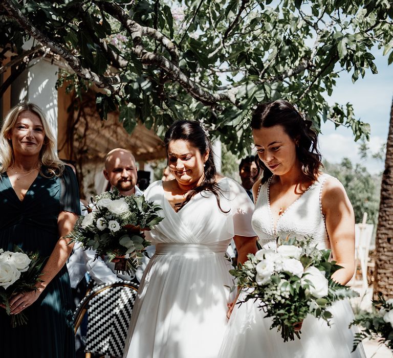 two-brides-carrying-white-flower-wedding-bouquets