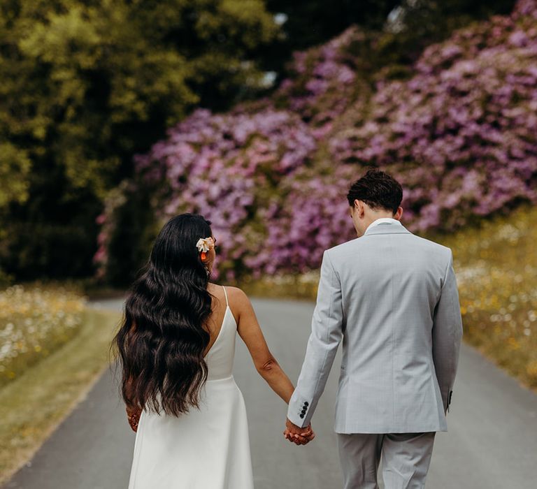 bride-with-long-wavy-black-wedding-hair-walking-hand-in-hand-with-groom