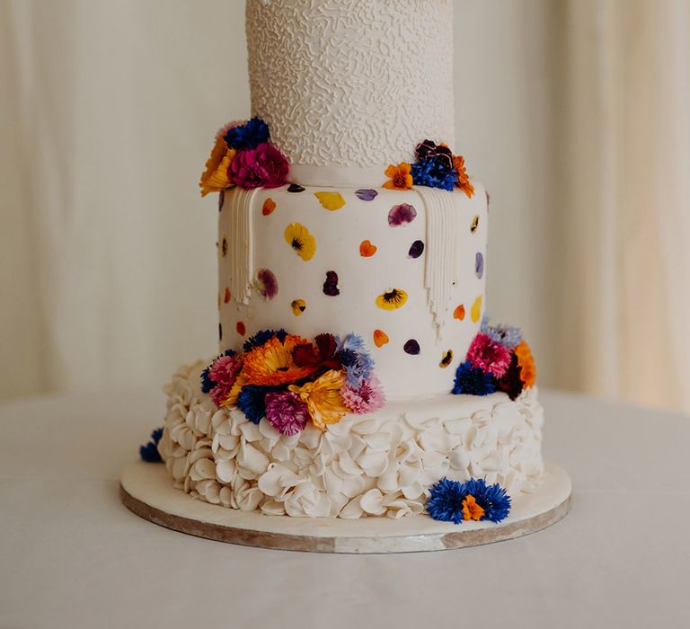 four-tier-white-iced-wedding-cake-with-purple-and-orange-flowers