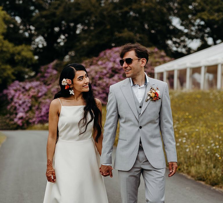 groom-wearing-light-grey-wedding-suit-with-sunglasses-smiling-at-bride