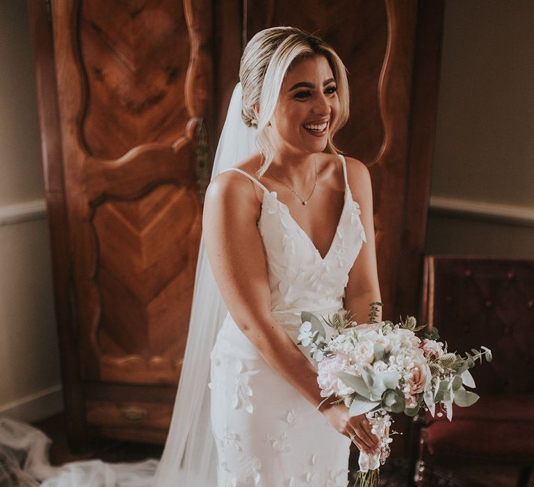 bride-holding-white-wedding-bouquet-in-flower-wedding-dress-with-floral-wedding-veil