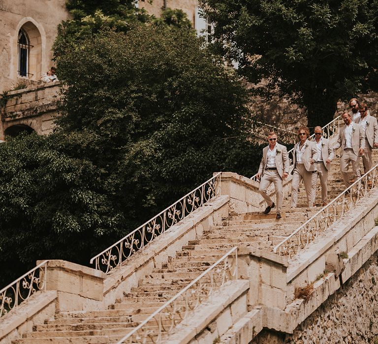 groomsmen-in-neutral-wedding-suits-walking-at-chateau-lagorce