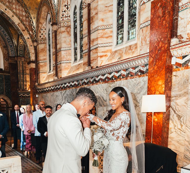 groom-kisses-brides-hands-at-church-wedding