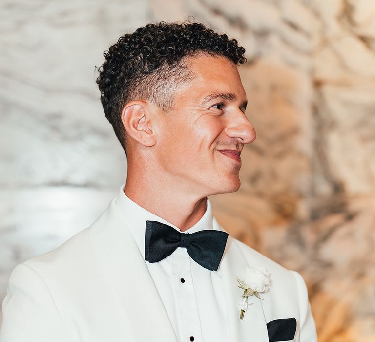 groom-wearing-white-tuxedo-and-black-bow-tie