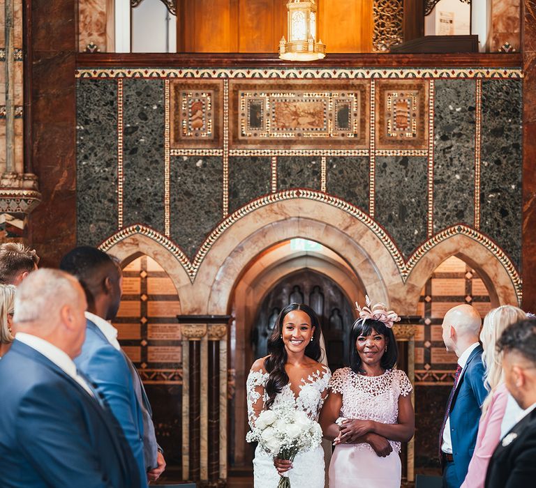 mother-of-the-bride-in-pink-dress-with-bride-in-lace-wedding-dress-walking-down-the-aisle