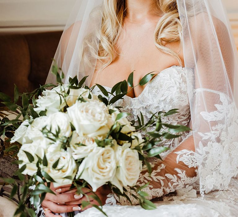 bride-in-lace-wedding-dress-with-veil-holding-white-rose-bouquet