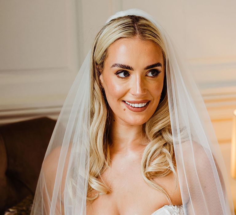 bride-in-strapless-wedding-dress-with-veil-and-crown-holding-rose-bouquet